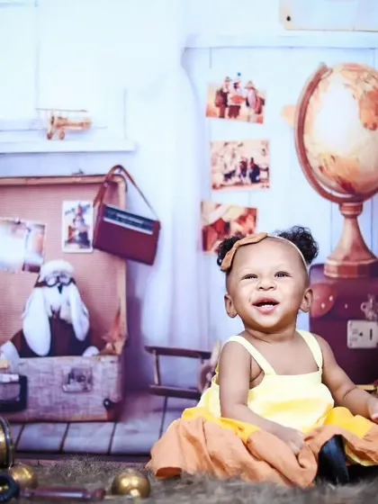 A happy baby girl in a yellow dress enjoying the vintage traveler themed set.