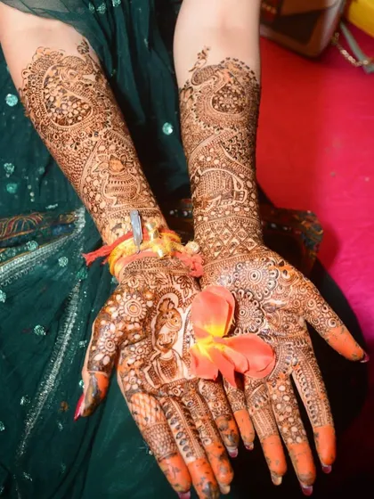 A full bridal mehndi, including a detailed bride and groom portrait. The arms are covered in traditional motifs like peacocks and elephants, creating a complete story.