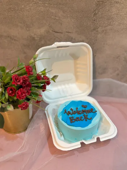 A simple blue bento cake with a "Welcome Back" message, ideal for celebrating someone's return home or to the office.