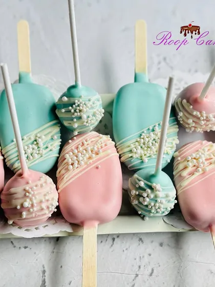 These modern cakesicles and cake pops are perfect for a gender reveal party. The treats are coated in pink and blue chocolate, finished with a white chocolate drizzle and pearl sprinkles for a touch of elegance.