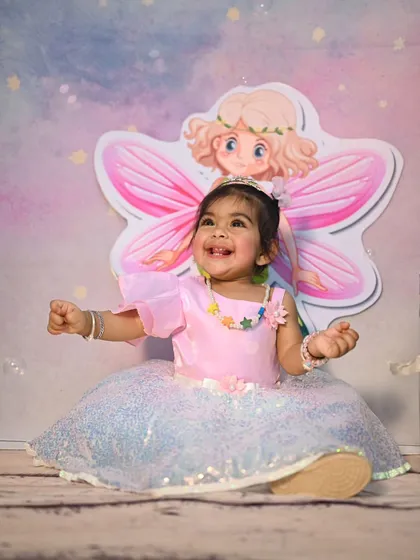 A joyful shot of the birthday girl dressed as a fairy. Our decor includes large, themed cutouts like this fairy with pink wings, creating a perfect photo spot.
