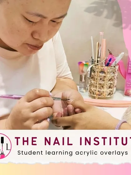 Here, a student is practicing acrylic overlays, learning how to create a thin, durable layer over the natural nail.