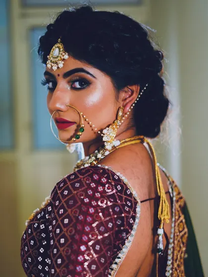 A powerful back-shot of a bride, focusing on the intricate hairstyle and the sharp, defined eye makeup.