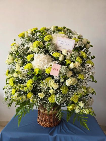 A grand and impressive floral basket arrangement, filled with a mix of white and lime green blooms for a fresh and vibrant look.