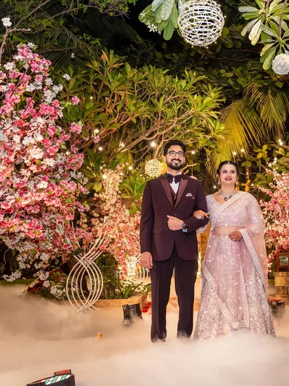 A beautiful, posed portrait of the couple at their reception, standing amidst the dreamy smoke and floral decor.