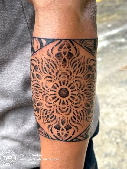 A dotwork mandala armband, showcasing another style of geometric tattooing. The shading is created entirely with tiny dots, giving the piece a soft texture and incredible depth.