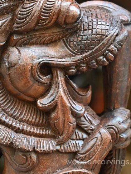 A detailed close-up of the head of the Yaazhi bracket. The intricate carving of the snout, teeth, and mane showcases the high level of skill required to create these pieces.