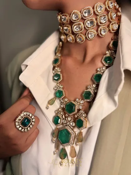 The power of two. A stunning emerald necklace is layered over a bold, uncut polki diamond choker, creating a rich texture and a look that is perfect for a cocktail party or reception.
