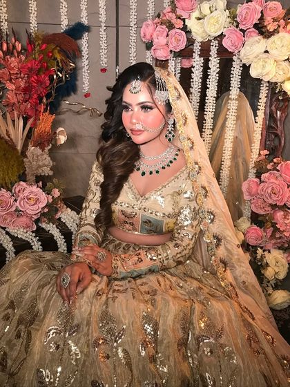 A full-length view of this gorgeous Pakistani-inspired look. The pastel-colored lehenga with gold work is perfectly complemented by soft, dewy makeup and a floral backdrop.