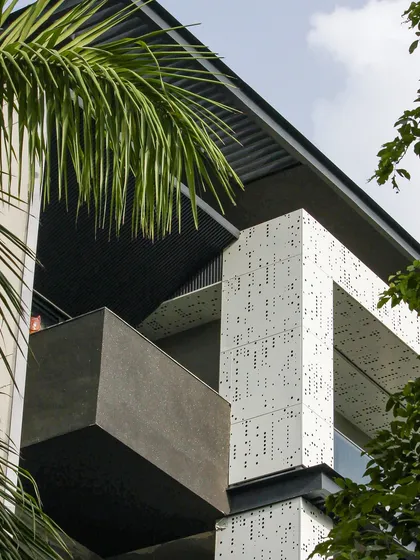 A worm's-eye view of the cube-form facade, highlighting the perforated jali on the underside of the balconies. This detail shows a commitment to design that extends to every surface.