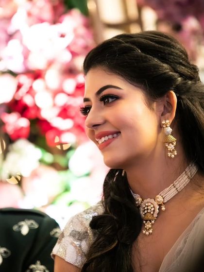 Another candid shot that captures the magic of a celebration. The makeup looks flawless and radiant even in a relaxed, joyful moment against a stunning floral backdrop.