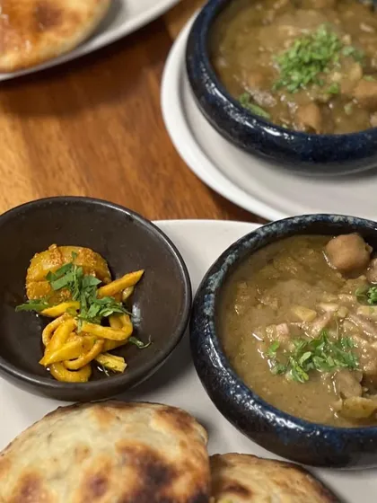 A comforting plate of Amritsari Chole served with fluffy, truffle oil cheese kulchas. The dish is accompanied by a side of homemade kairi achaar for a tangy kick.