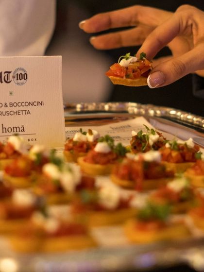 A guest selects a Tomato & Bocconcini Bruschetta from a passed tray. Our canapés are always fresh, flavorful, and easy to enjoy while mingling at a brand event.