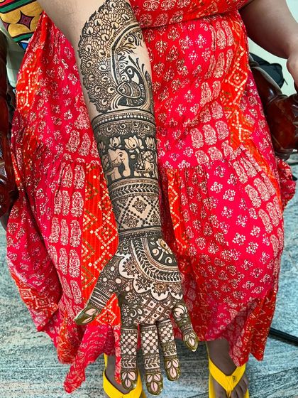 A beautiful bridal mehendi for Malavika, featuring a large peacock design on the forearm, complemented by elephant motifs and traditional patterns on the hands.