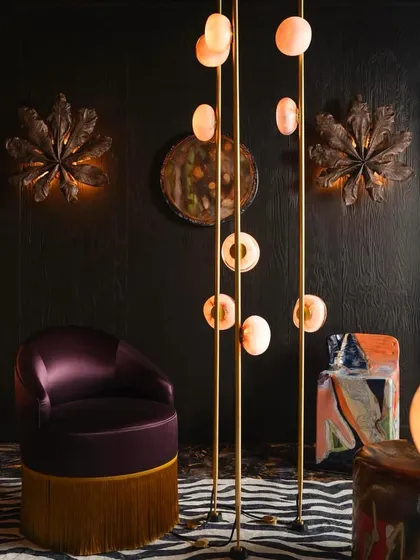 The Bocci 84 series, seen here as floor-to-ceiling columns in a dramatic, dark interior. The light illuminates the delicate copper mesh inside the glass spheres, creating a warm, textured glow.
