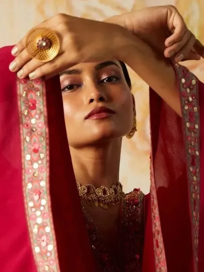 A close-up from a designer lookbook shoot, focusing on a soft yet impactful editorial makeup look. The blended pink eyeshadow and defined lip color complement the model's features without overpowering the intricate jewelry and garment details, making it perfect for fashion-forward campaigns.