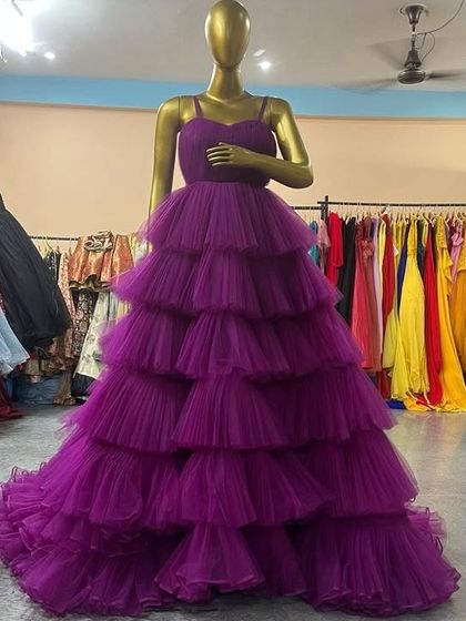 A beautiful purple gown with a spaghetti strap top and a full, multi-layered ruffled skirt, perfect for a grand entrance.