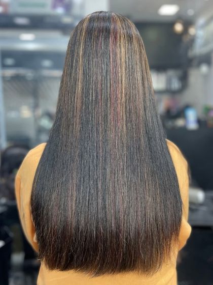 This image showcases a straightening treatment on dark hair with subtle highlights. The sleek finish makes the color variations pop while ensuring the hair looks polished and healthy.