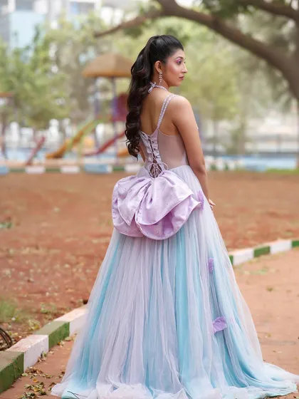 A view from the back, showcasing the corset detail of the dress and the voluminous hairstyle.