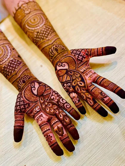 A slightly different angle of the peacock-centric bridal mehendi, showing the flow of the design from the palm to the fingers.