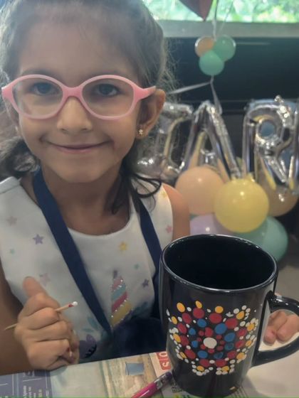 The birthday girl, Kiara, looking delighted with her colorful dot mandala creation.