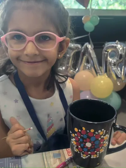 The birthday girl, Kiara, looking delighted with her colorful dot mandala creation.