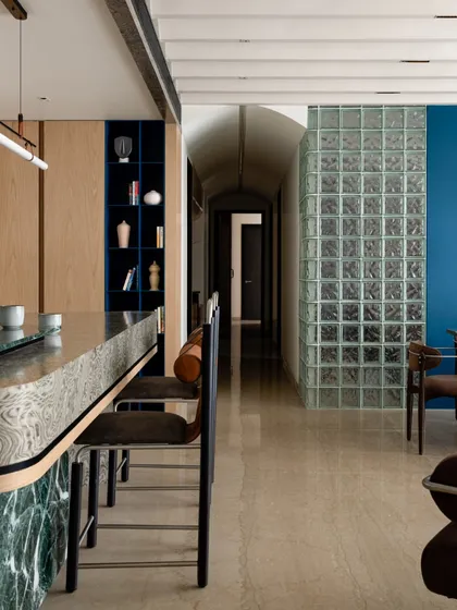 This view highlights the home's open layout, with the breakfast bar, dining area, and arched passage all visible. We used glass blocks and a bold blue accent wall to define the dining space while maintaining a visual connection to the rest of the home.
