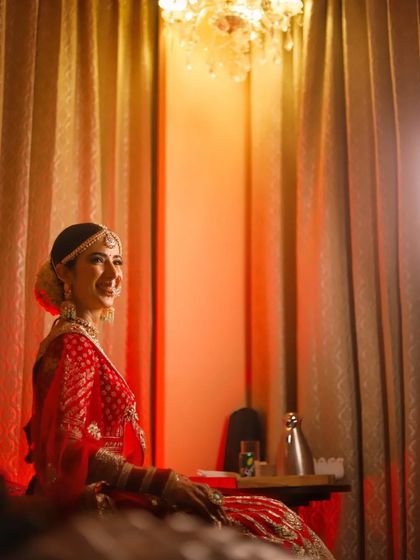 A candid-style portrait of a bride smiling, captured in a room with warm, ambient lighting.