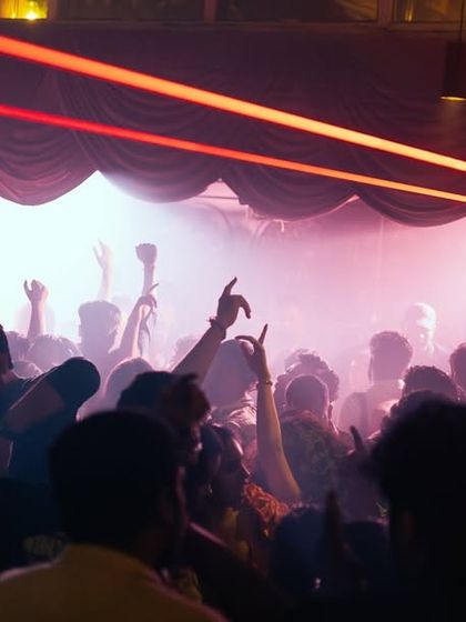 The crowd with their hands up under the dramatic red lasers.