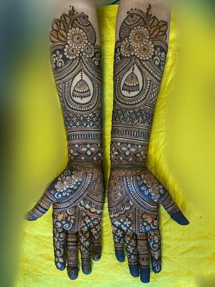 This design features beautiful jhumka (bell) elements within ornate arches on the forearms, complemented by floral patterns on the palms.