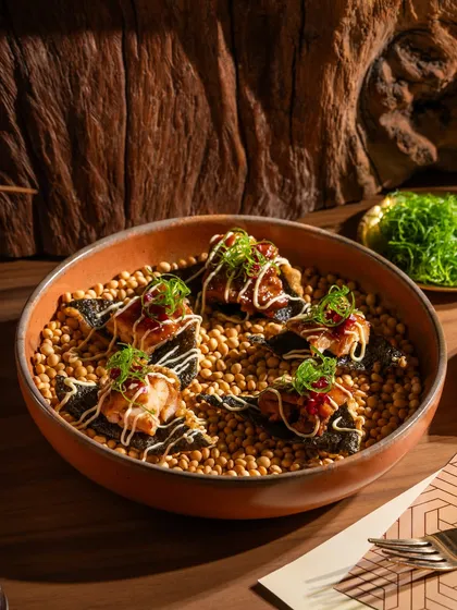 Teriyaki chicken bites on nori crisps. The presentation on a bed of soybeans is unique and adds texture to the photo.