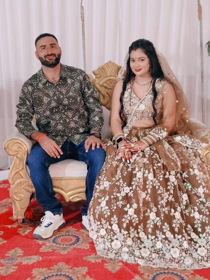 The happy couple seated together, with the bride-to-be looking lovely in her brown floral lehenga.
