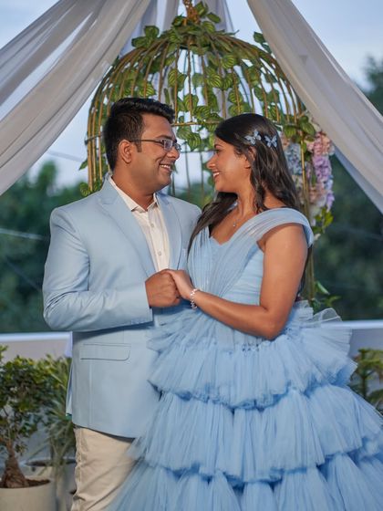 A joyful couple's maternity photo. The bride-to-be is wearing our 'Charm' gown, a tiered tulle creation in a lovely shade of powder blue.