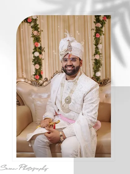 A smiling portrait of the groom seated, holding a ceremonial sword, looking happy and relaxed.