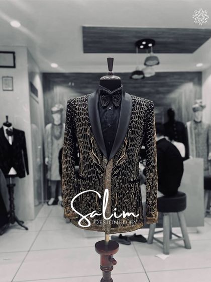 A mannequin displaying a black and gold tuxedo jacket with an intricate, armor-like pattern. This is a powerful and luxurious design for a formal event.