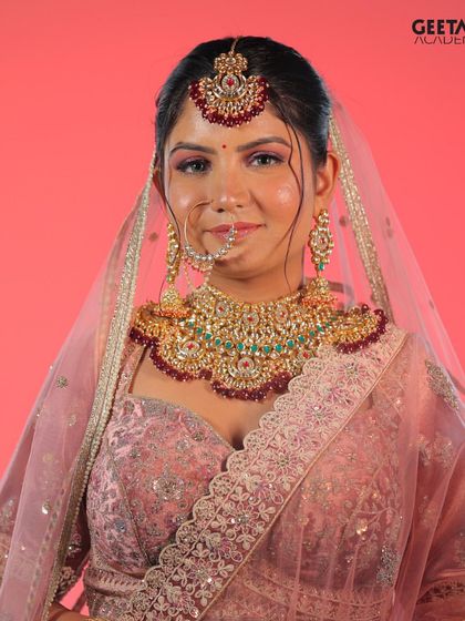 Student Work: This vibrant bridal look features a bright pink lehenga and flawless makeup with a dewy finish, demonstrating our students' command of color and technique.
