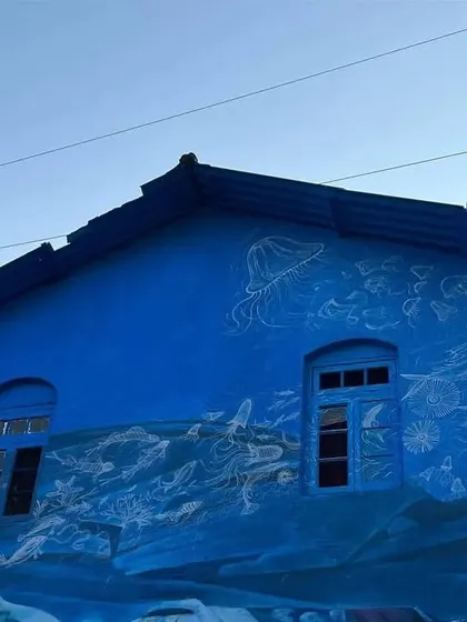 A beautiful blue mural at Sassoon Dock, with delicate white line drawings depicting scenes of the sea. The artwork covers the entire facade of one of the dock's buildings.