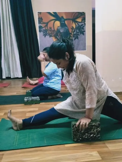 Here, a student deepens her stretch in a supported front split. This demonstrates how we work on increasing flexibility over time with safe and effective methods.
