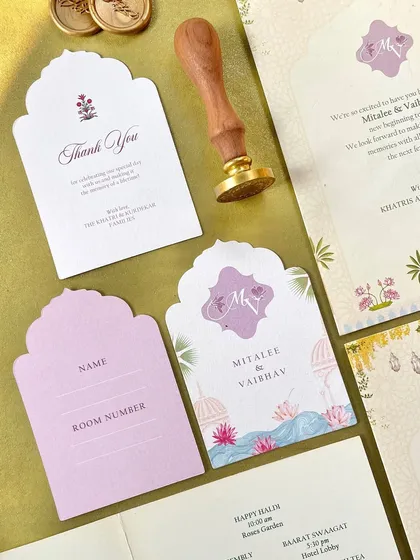 A collection of day-of items for a wedding in Udaipur, including a thank-you note, a luggage tag with a custom monogram, and other small cards, all featuring the beautiful palace-inspired illustrations.