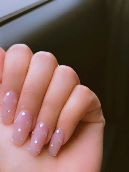 A clear, still image of the sheer pink nails with minimalist rhinestone dot accents.