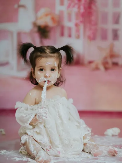 Another angle of her enjoying the cake, showing the soft, pretty details of the studio setup in the background.