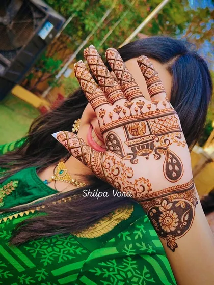 A client showing off her festive mehndi, which includes a 'palki' (palanquin) design, often used in bridal art.