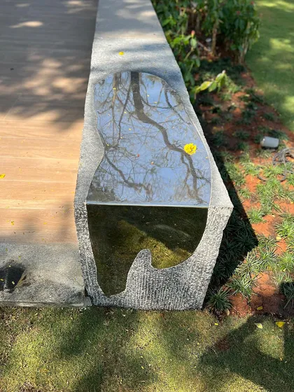 The "Kagami" bench, a handcrafted piece of stone with a polished steel inlay that reflects the sky and tree branches above. This bench is an ode to Dali, designed as a poetic canvas where one can pause and reflect.