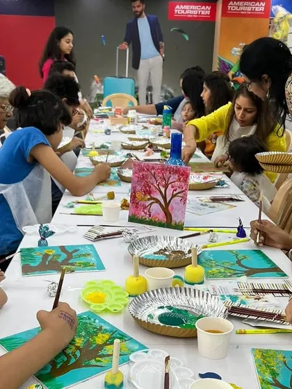 A full house of creativity! Our 'Palette Harmony' workshop brings moms and kids together around a long table for a shared session of guided canvas painting.