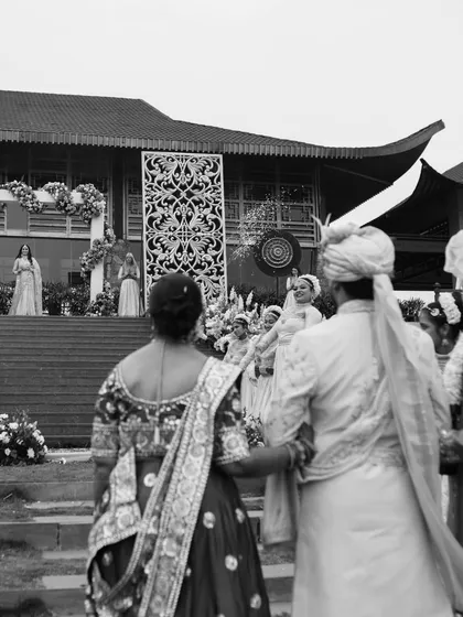 A black and white shot from the perspective of the family, watching the couple during their grand wedding ceremony. It highlights the importance of family in the celebration.
