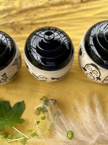 Another perspective of the finished jars, sitting on a lovely yellow cloth that makes the black and white designs pop.