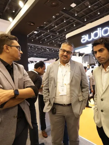 A candid moment of networking between three professionals in the AV section of the expo, showcasing the collaborative atmosphere.