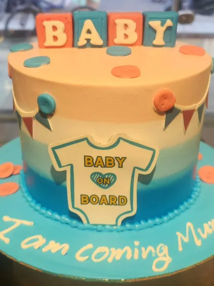 A sweet cake to celebrate a new arrival. This "Baby on Board" cake is perfect for a baby shower, with its gentle color gradient, baby blocks, and an adorable onesie design.
