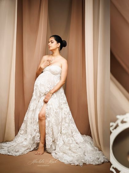 A serene and artistic pose in a beautiful white lace gown, using soft drapes in the background to create a gentle, enclosed space.
