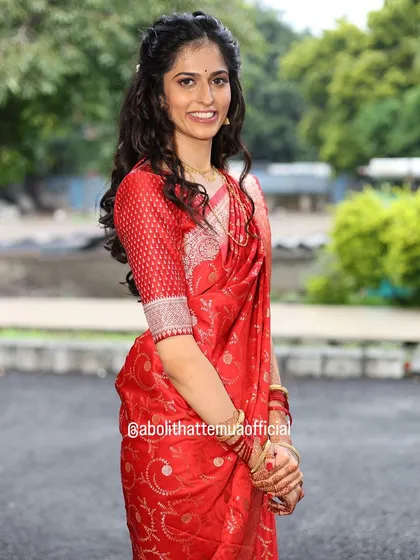 A full-length shot of the bride in her beautiful red saree. The simple makeup and hairstyle create a look of timeless elegance for her pre-wedding event.